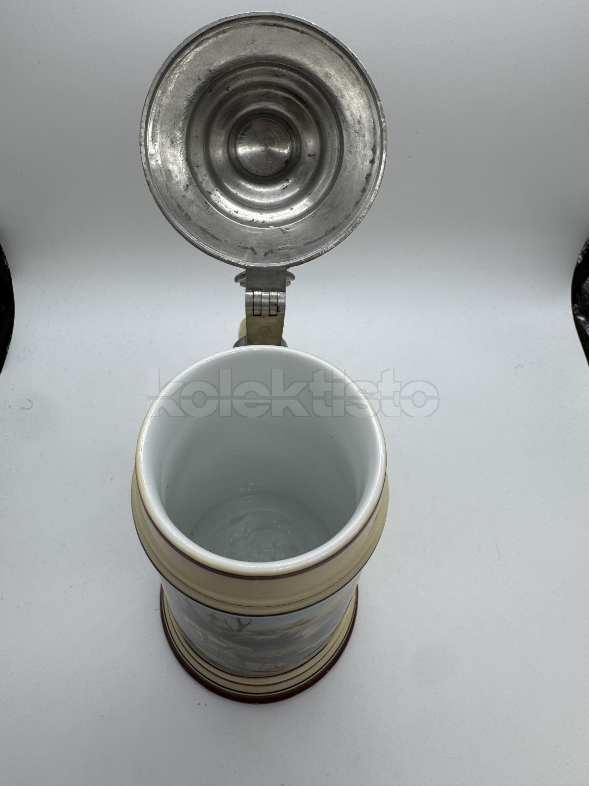 Porcelánový korbel s cínovým víkem a malbou s loveckým motivem, na dně průsvitka