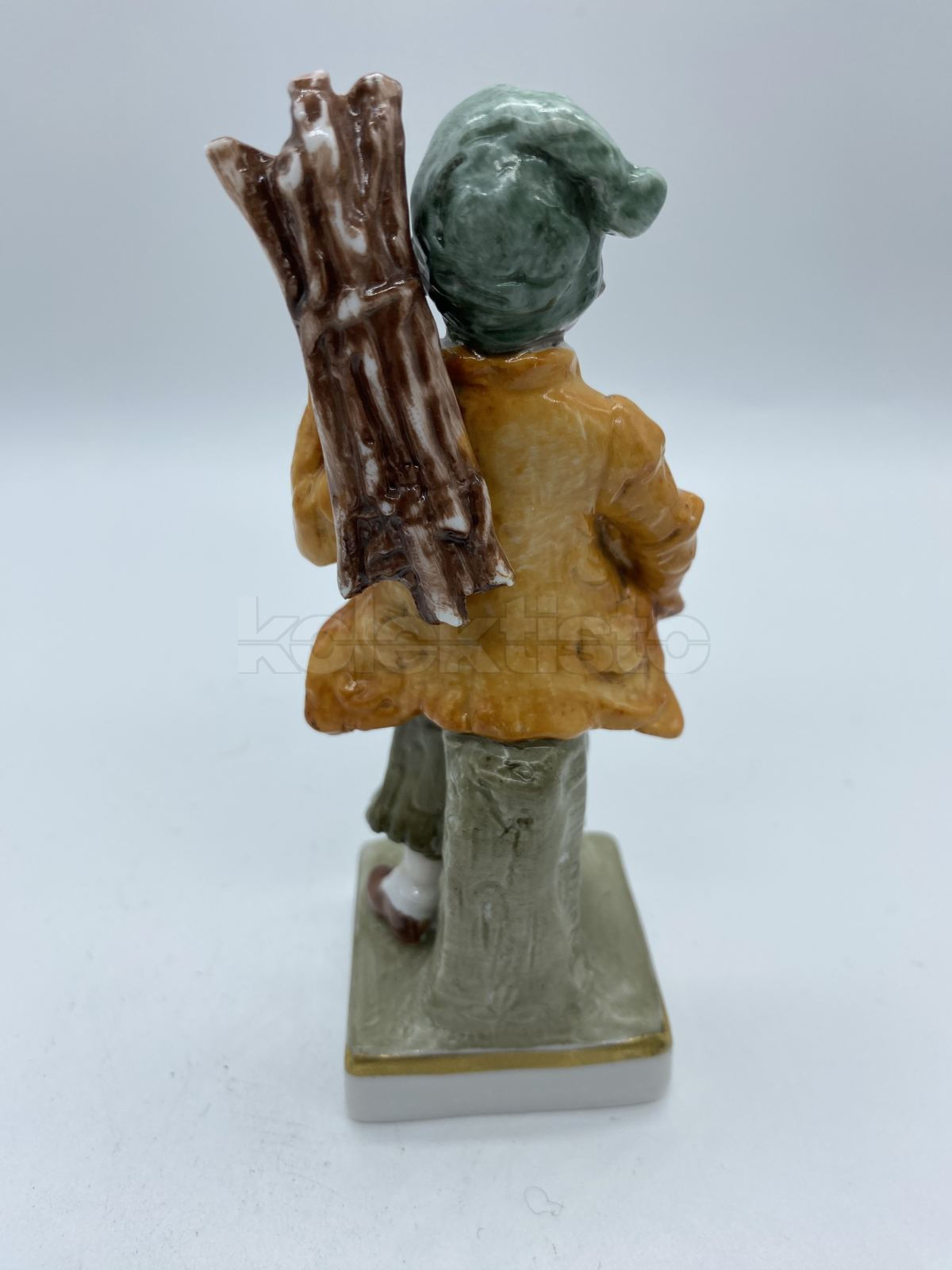 Porcelánová soška chlapce nesoucí klestí