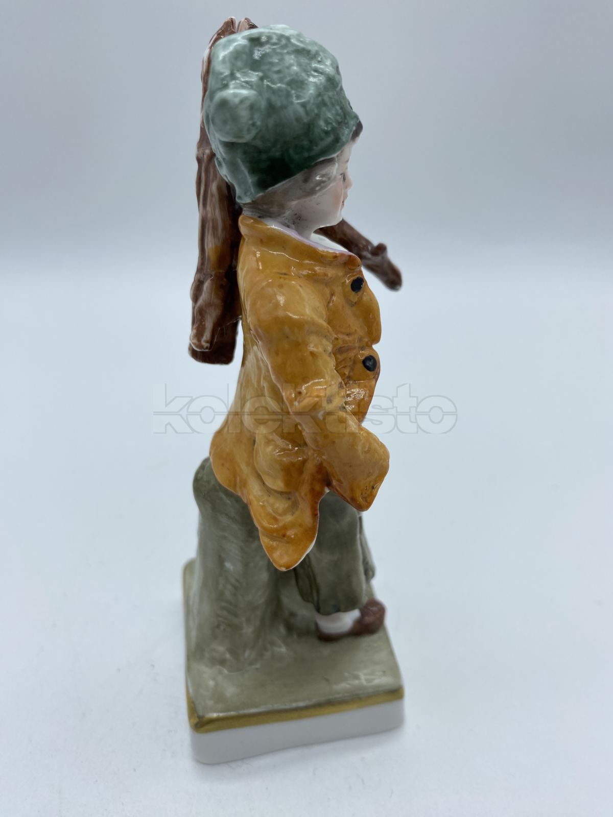 Porcelánová soška chlapce nesoucí klestí