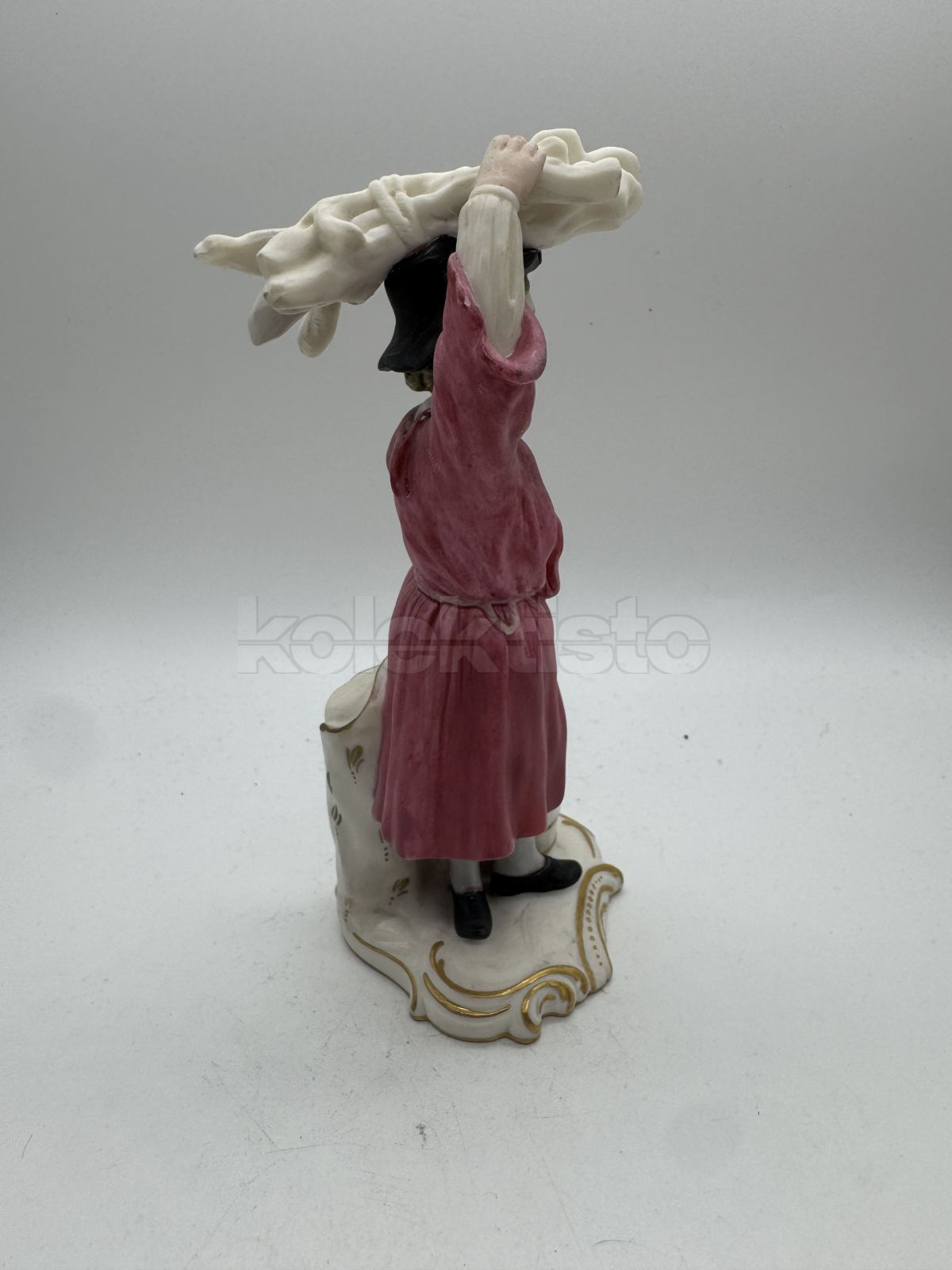 Porcelánová soška muže nesoucího klestí