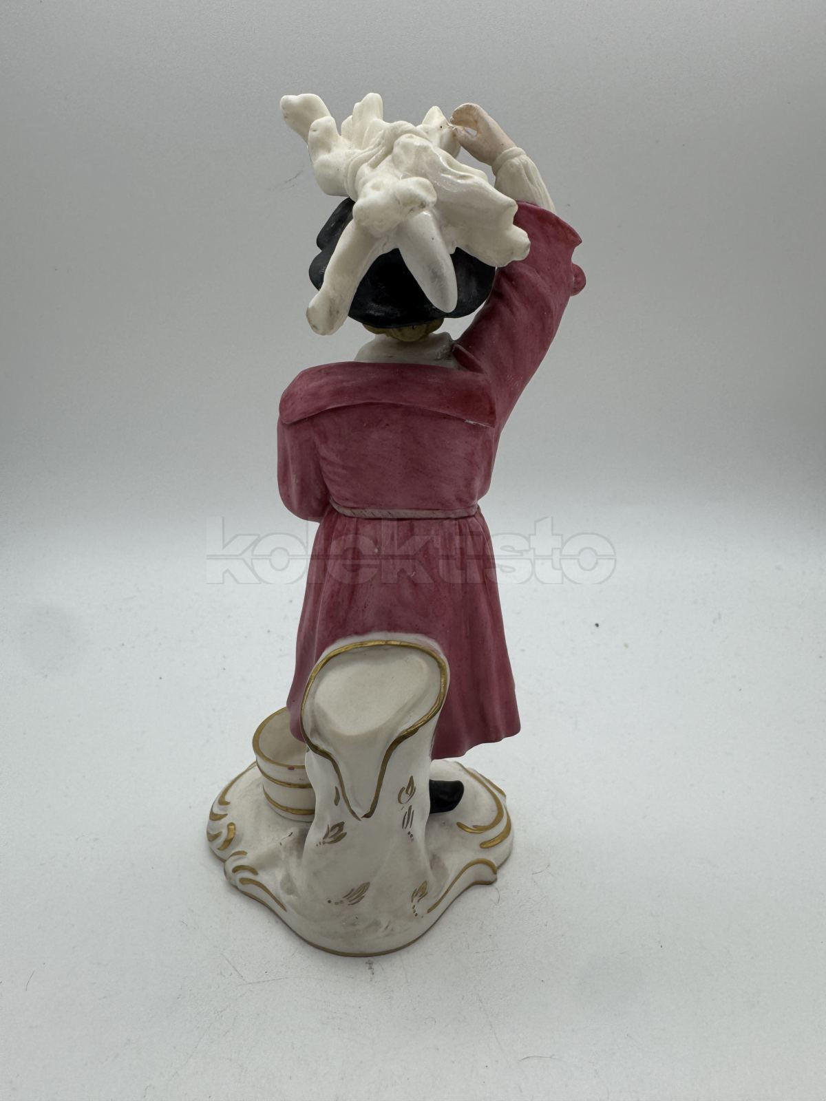 Porcelánová soška muže nesoucího klestí
