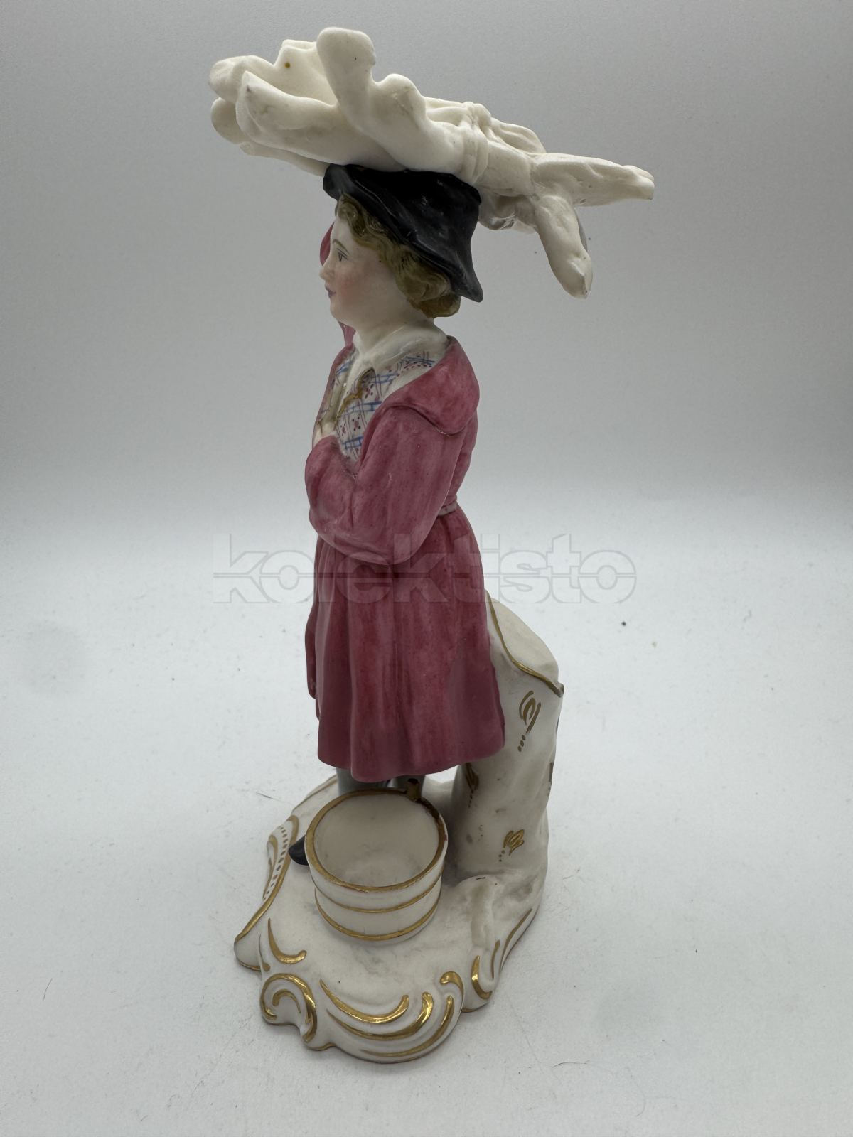 Porcelánová soška muže nesoucího klestí