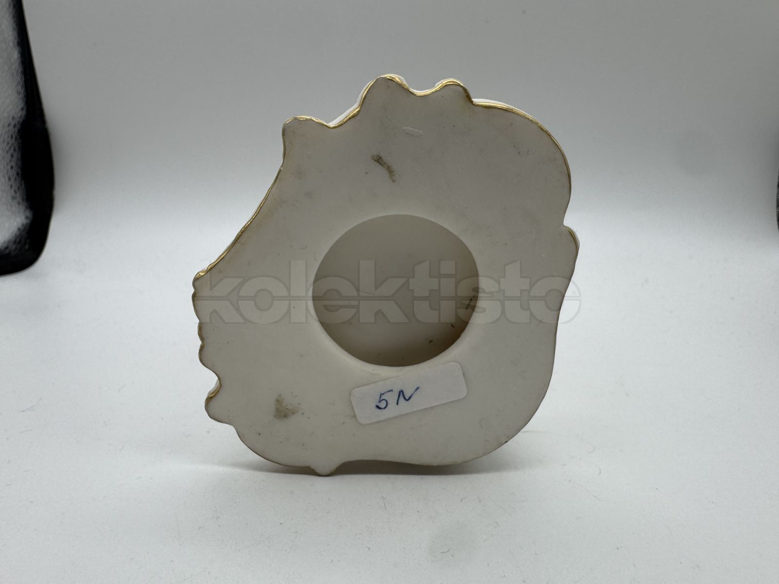 Porcelánová soška muže nesoucího klestí