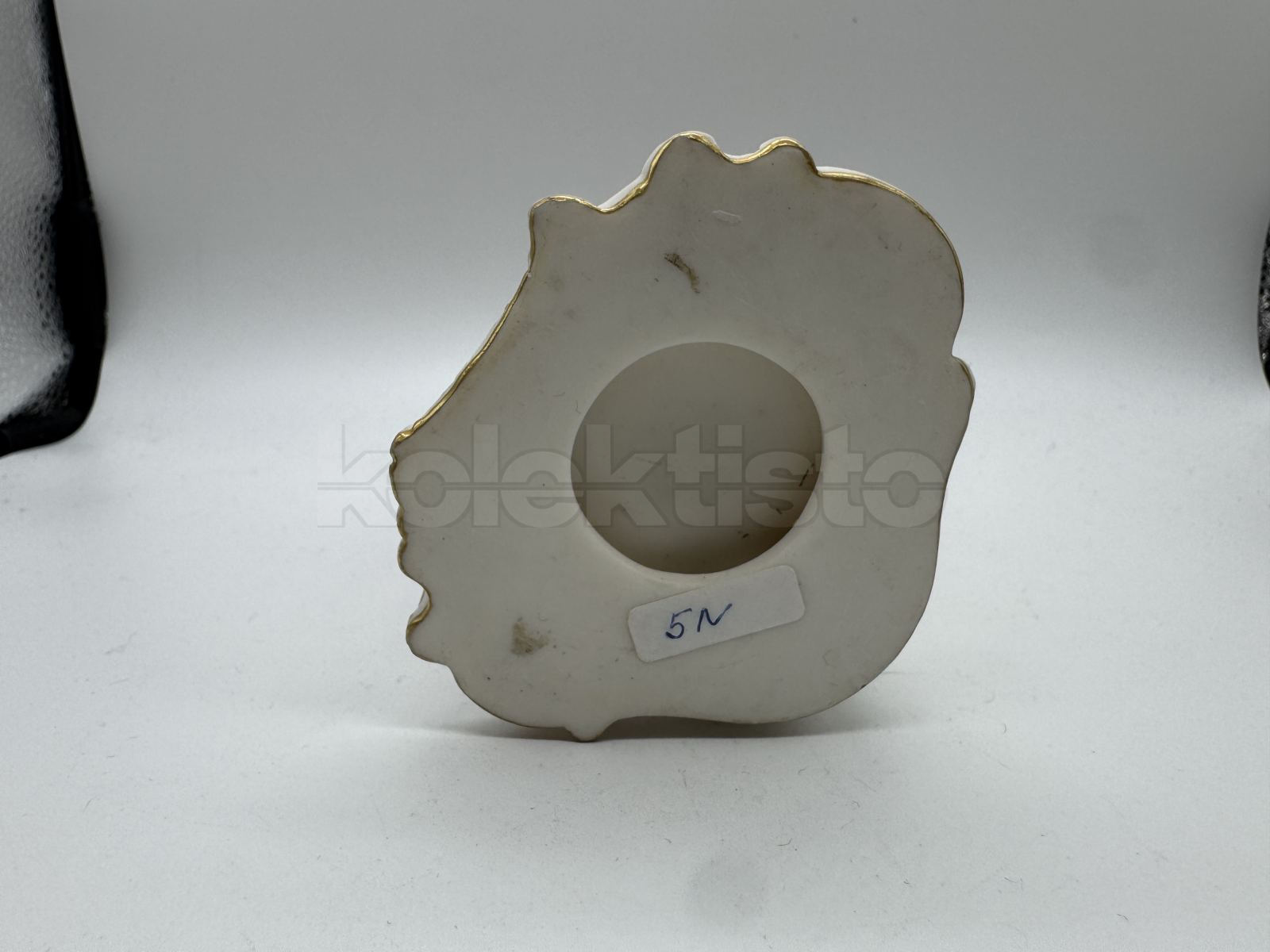 Porcelánová soška muže nesoucího klestí