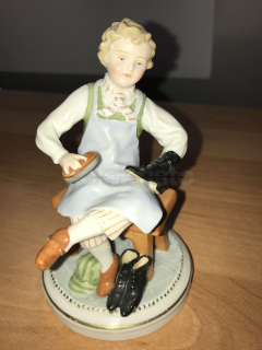 Porcelánová soška dítěte čistící si boty