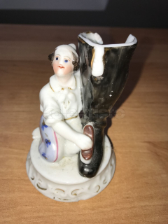 Porcelánová soška chlapce leštícího boty