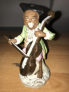 Porcelánová soška opice hrající na basu